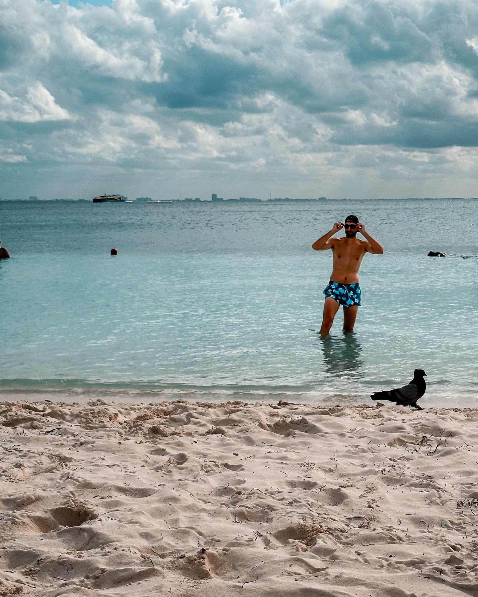 Ein Mann steht am Strand im Wasser und blickt auf den Strand