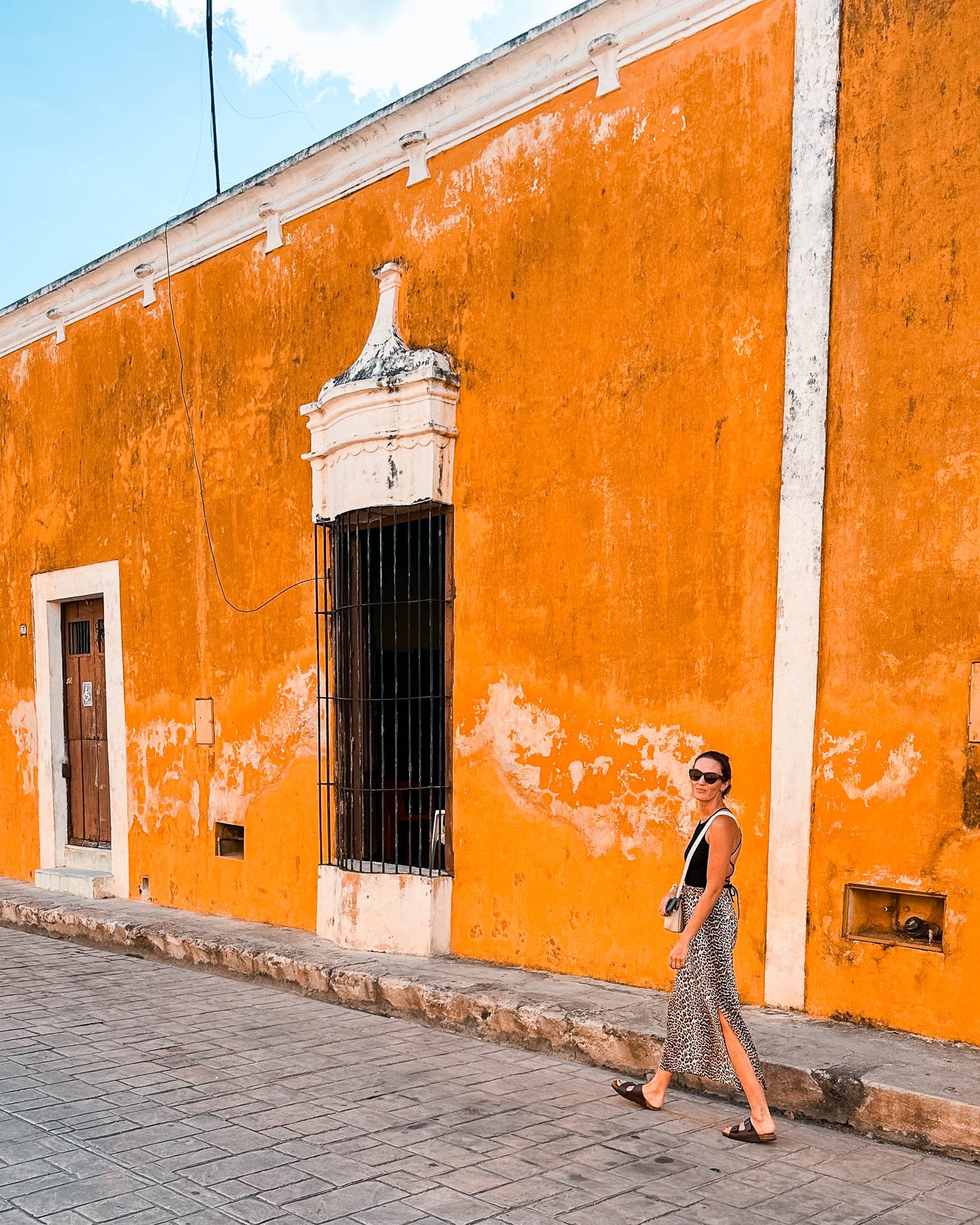 Junge Frau läuft vor gelben Häusern in Izamal