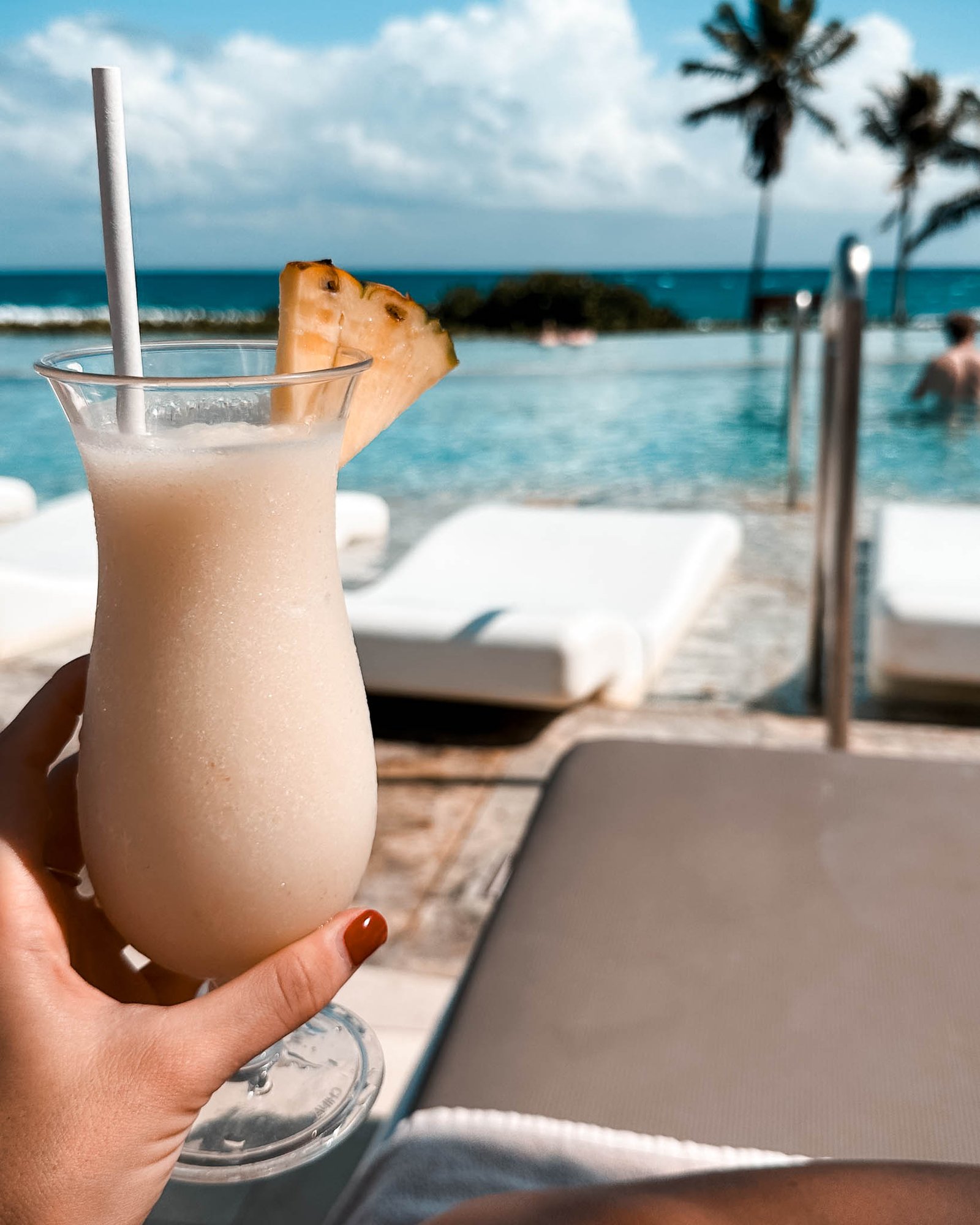 Ein Pina Colada Cocktail in der Hand einer Frau