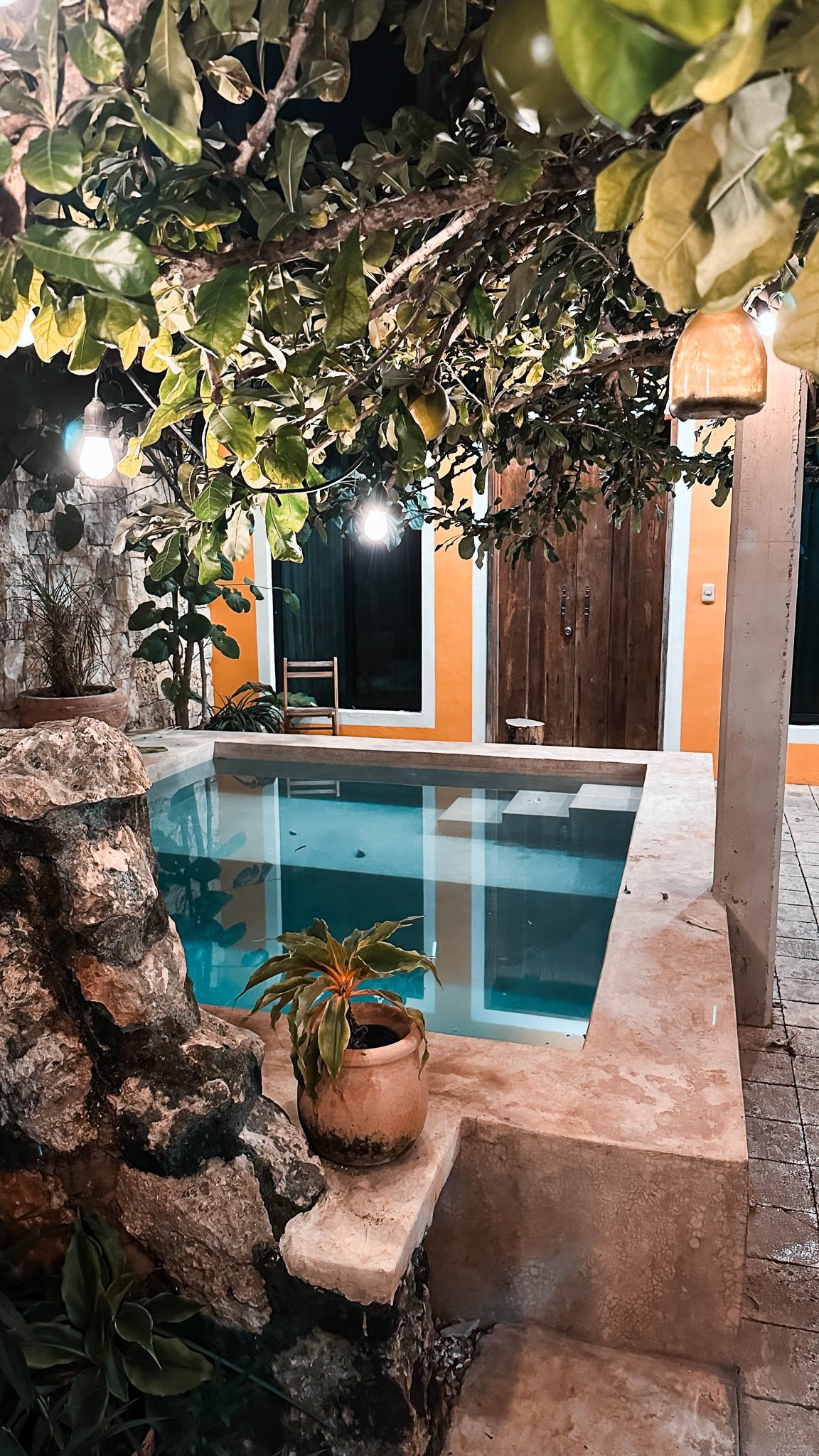 Kleiner süßer Innenhof mit einem Pool darüber ein Baum und neben dem Pool eine Skulptur