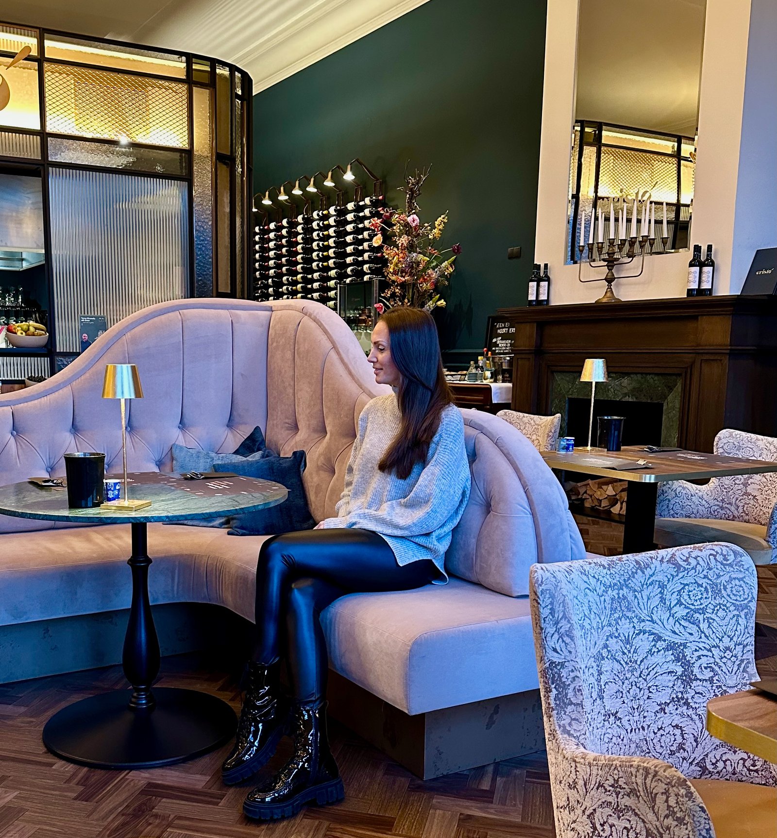 Eine junge Frau sitzt auf einem großen Ecksofa im Restaurant des Hotels Mondragon