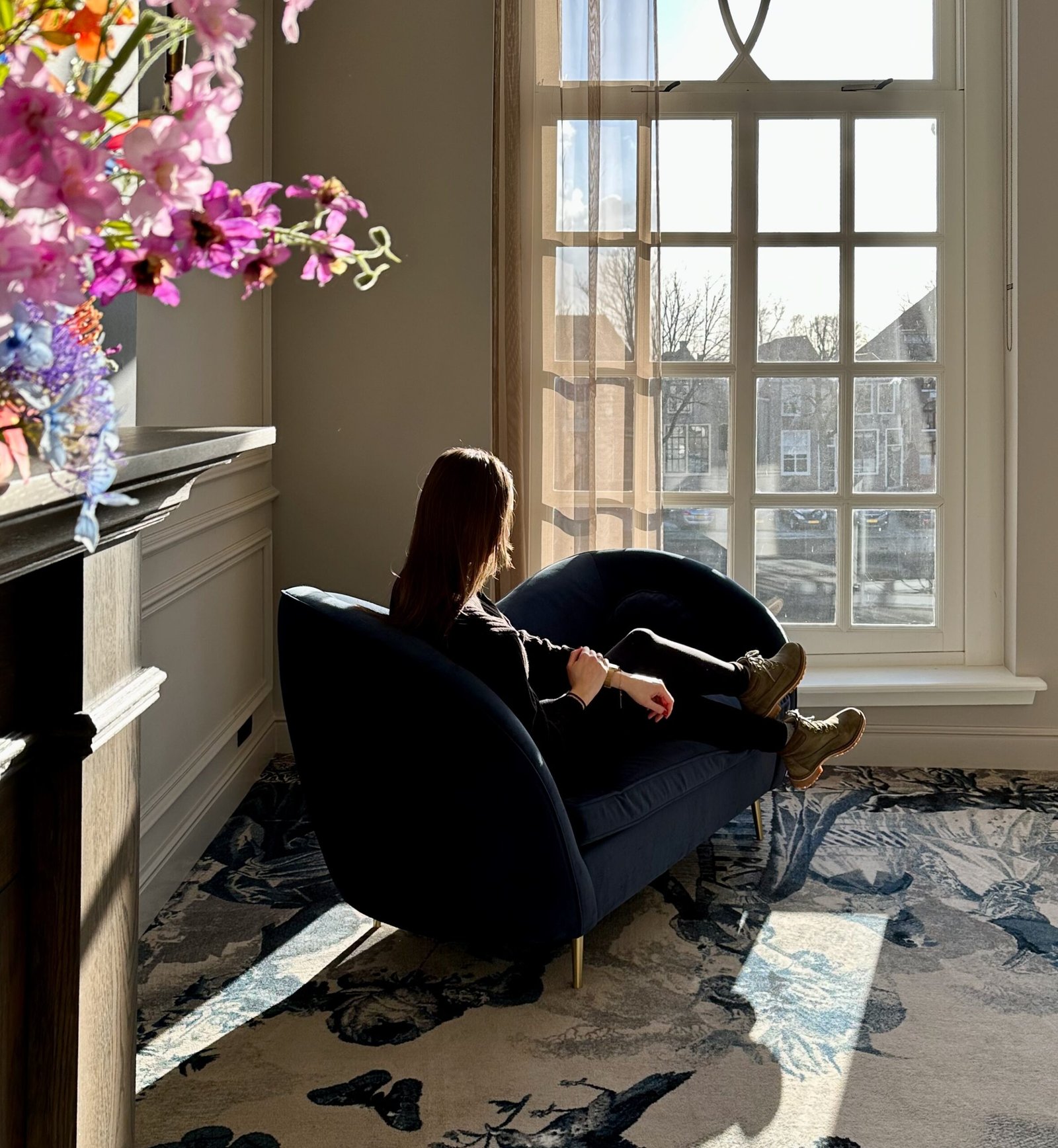 Eine Frau sitzt auf einem Sofa und schaut aus dem kleinen Fenster auf die Straße