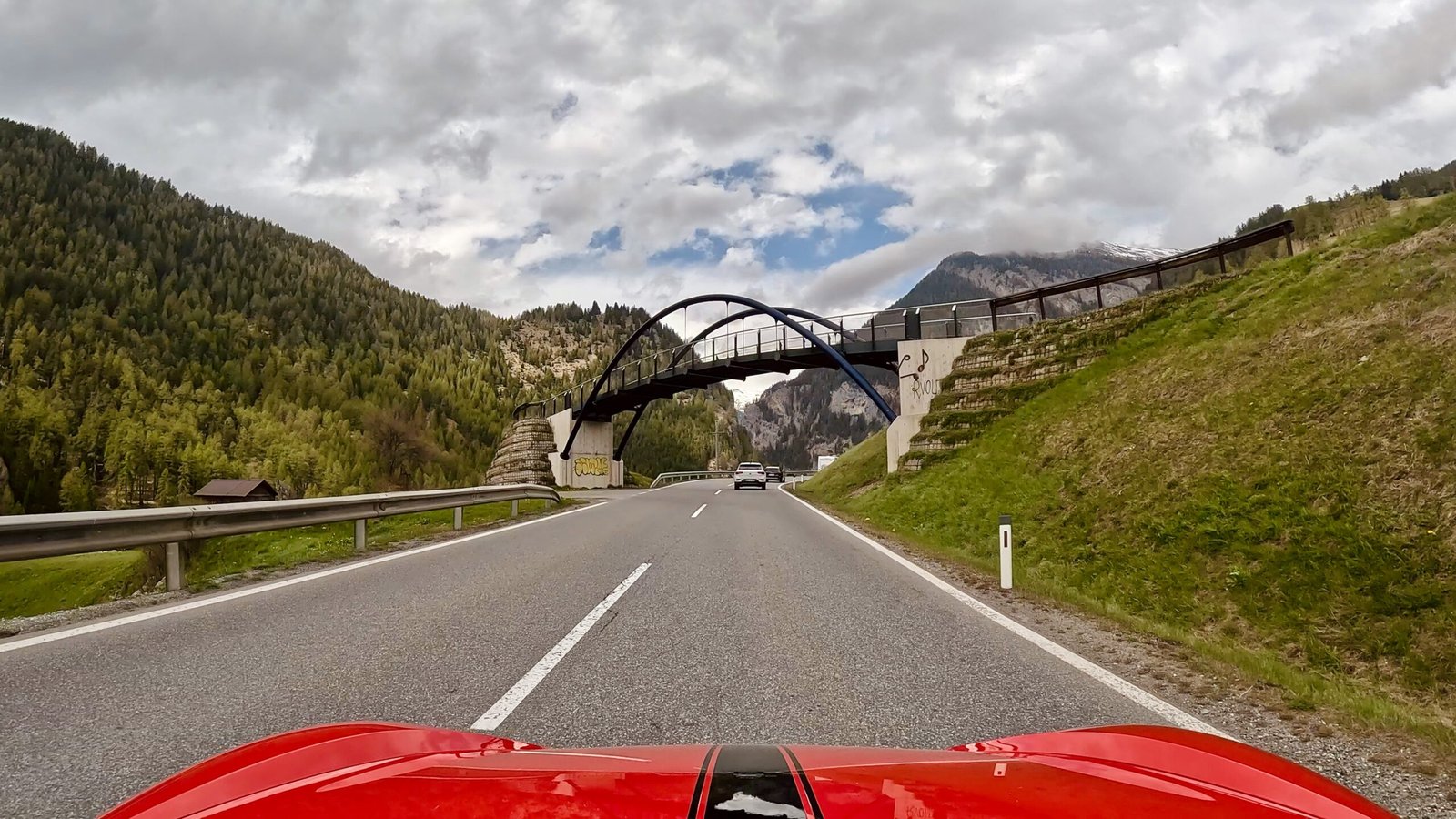 Perspektive des Fahrers zeigt eine Brücke vor Bergpanorama auf dem Reschenpass